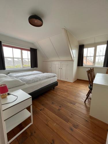 东卡佩勒Het Landhuis的一间卧室配有一张床、一张书桌和两个窗户。