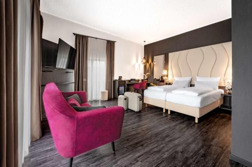 海尔布隆卡斯特尔最佳西方酒店的酒店客房,配有一张床和一张粉红色的椅子