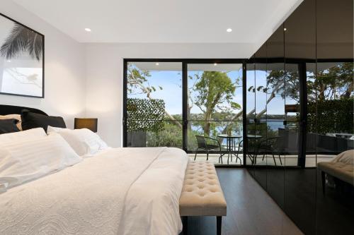 悉尼Luxury Waterside Home Sanctuary的一间带一张白色大床的卧室和一个阳台