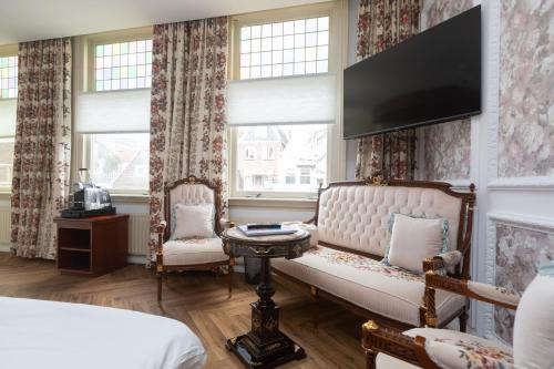 代尔夫特代尔夫特约翰尼斯·维米尔酒店的一间带沙发和电视的墙壁卧室