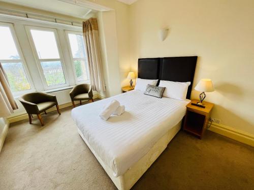 迪斯伯里Heath Cottage Hotel的一间卧室配有一张床、两把椅子和窗户
