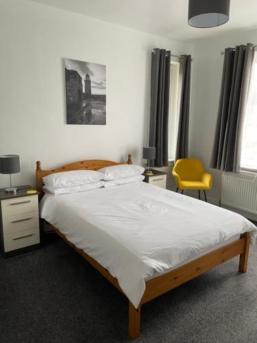 波特帕特里克布林克伯尼旅馆的一间卧室配有一张床和一张黄色椅子