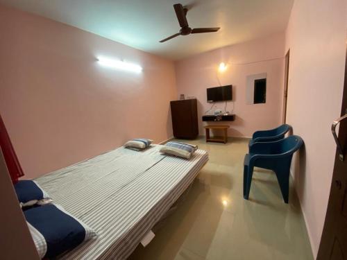 VānūrFamily Guest House Pondicherry的一间设有床铺和蓝色椅子的房间