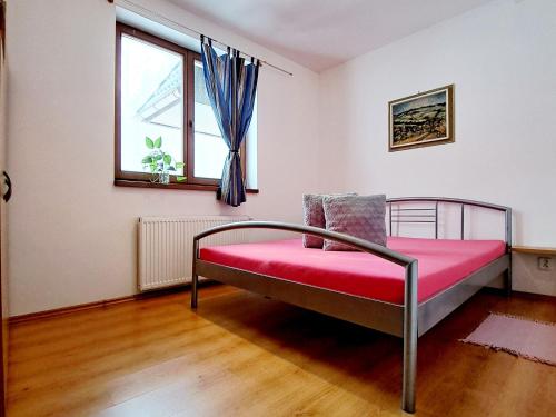 高塔特拉山Apartmán Severanka的一间卧室配有一张带红色毯子的床和窗户。