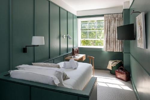 伦敦The Goodenough Hotel London的绿色卧室设有床和窗户