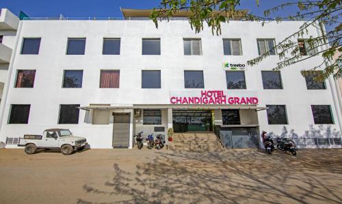 钱德加尔Treebo Trend Chandigarh Grand的一座白色的建筑,前面停有摩托车