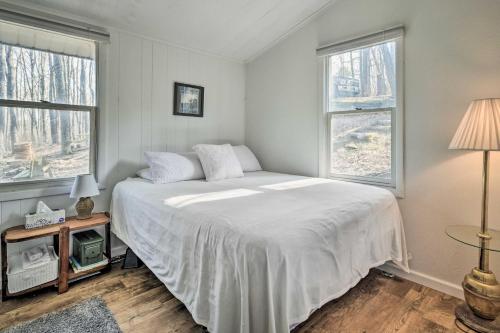 Unplugged Mountain Retreat with Porch Swings!的卧室配有白色的床和2扇窗户。