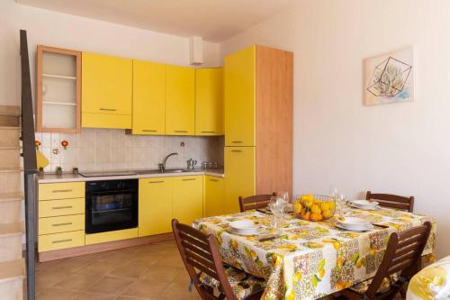 诺托玛丽娜Villa vista mare ~Villa Dafne~的厨房配有黄色橱柜和带桌布的桌子