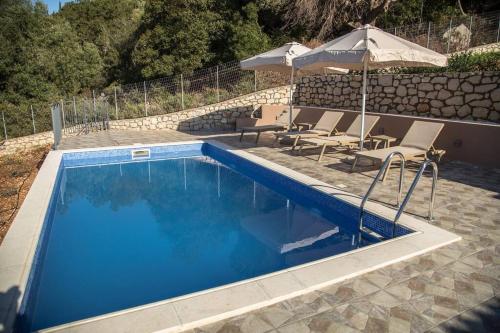 PisaëtósVilla Odysseus的蓝色游泳池配有椅子和遮阳伞
