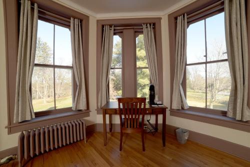 奥内达Oneida Community Mansion House的客房设有窗户、桌子和椅子。