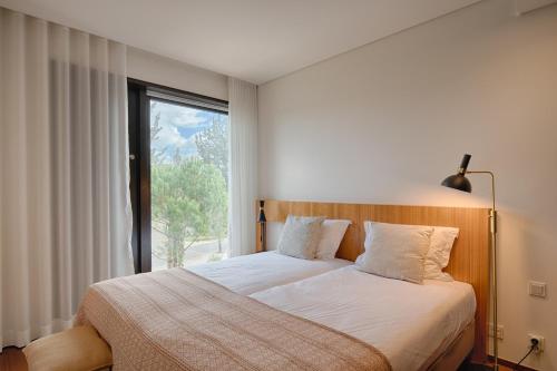 特罗亚Tróia Resort Beach Villa的一间卧室设有一张大床和大窗户