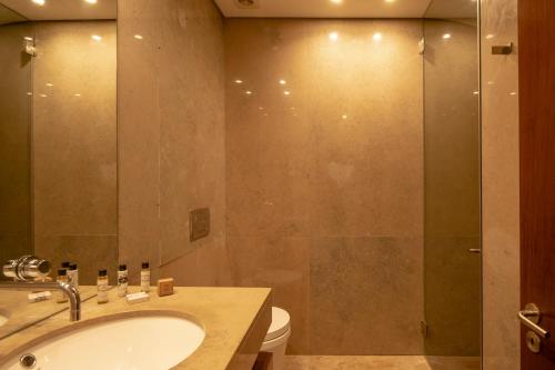 特罗亚Tróia Resort Beach Villa的一间带水槽和玻璃淋浴的浴室