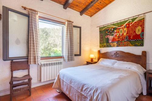 赫罗纳Casa con piscina cerca de Girona的一间卧室设有一张床、一个窗口和一把椅子