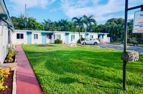 哈兰代尔海滩Hallandale Beach Motel with Free Parking and Full Kitchen !的绿色庭院,设有建筑和停车场