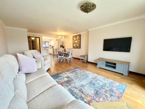 桑当3 Bedroom house - Sandown的客厅配有白色沙发和平面电视。