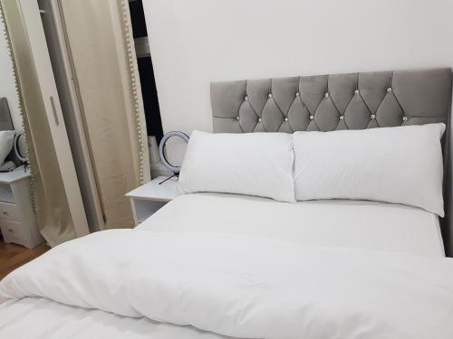 罗瑟勒姆Elegant room In a private House的一张带白色床单和灰色床头板的床
