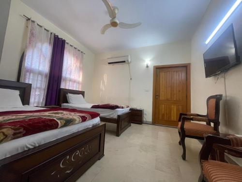 伊斯兰堡Dream Palace的一间卧室设有两张床、一台电视和一把椅子