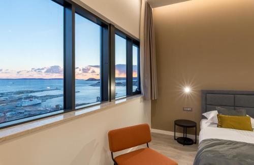 斯普利特Seascape Luxury Rooms的一间卧室设有大窗户、一张床和椅子