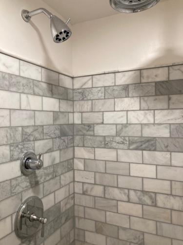 丹佛Pineapple House, Cozy Garden Apartment, City Center! Marble-Tiled Bathroom! FREE parking!的浴室铺有灰色和白色瓷砖,设有淋浴。