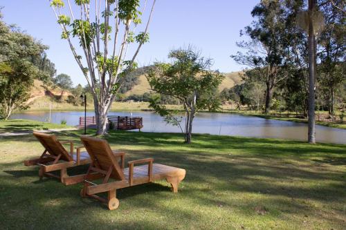 库尼亚POUSADA SERTÃO DA BOCAINA的两把椅子坐在湖边的草地上
