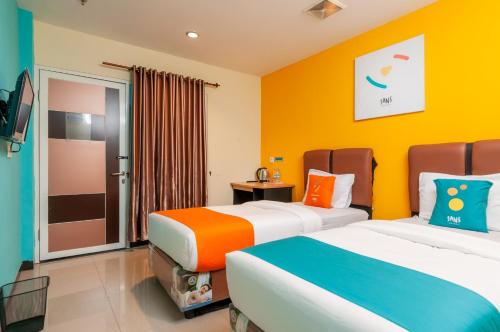 棉兰Sans Hotel Finest Medan的一间酒店客房,设有两张床和电视