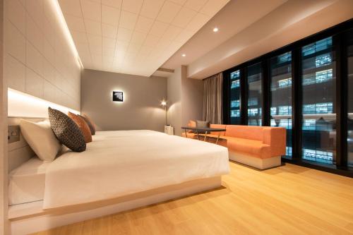 东京karaksa hotel colors Tokyo Yaesu的卧室配有一张白色的大床和一张沙发。