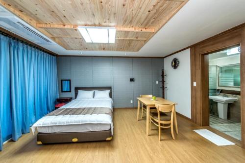 西归浦市Sea and Wave的一间卧室配有一张床、一张桌子和蓝色窗帘