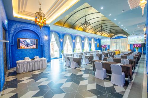 乌隆他尼Amman Unique Hotel - SHA Plus的一间拥有蓝色墙壁和白色桌椅的房间