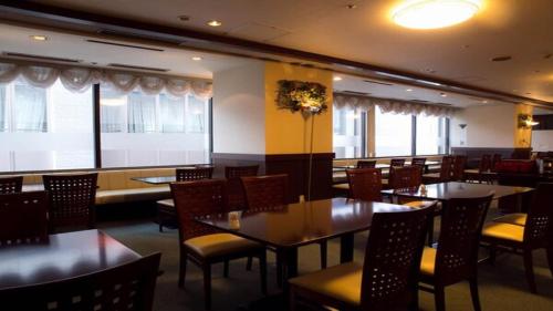 盛冈HOTEL BRIGHT INN MORIOKA的用餐室设有桌椅和窗户。