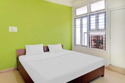 瓜廖尔SPOT ON Ganesh Guest House的绿色的客房设有窗户,配有一张白色的床。