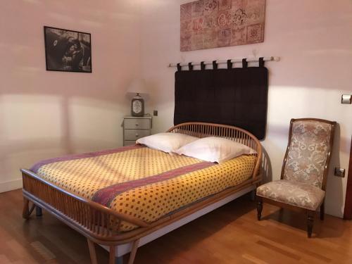 卢瓦尔河畔圣西CoTTAGE LA VILLA BOLERO的一间卧室配有一张木床、椅子和时钟