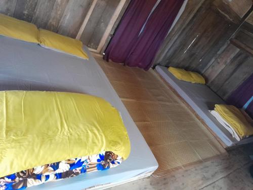 和平Mường Ecolodge Hòa Bình的小客房内的两张床,配有黄色床单