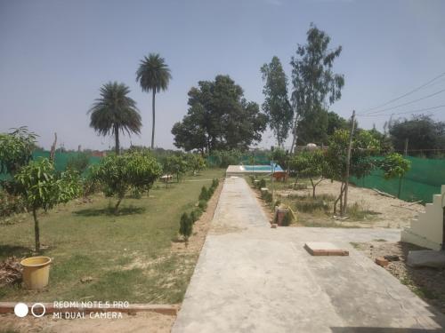 KannaujBraj Waterpark & Resort的一条有树木和栅栏的田野上的道路