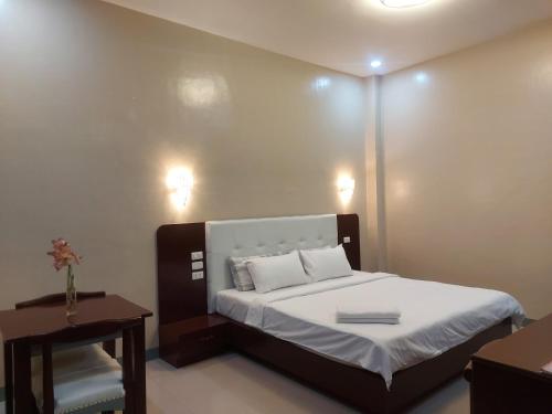 第波罗B&S Orchids suites hotel的一间卧室配有一张带白色床单和一张桌子的床。
