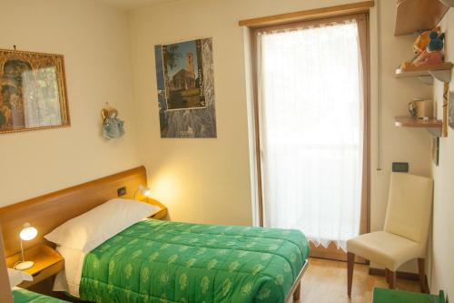 加尔达湖滨Appartamento Lombardi的一间卧室设有一张床、一个窗口和一把椅子