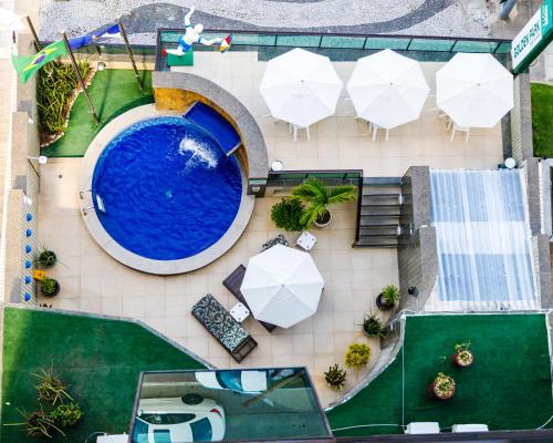 累西腓Hotel Golden Park Recife Boa Viagem的享有带桌子和遮阳伞的游泳池的顶部景致