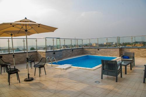 杜阿拉Geneva Hotel的屋顶游泳池配有椅子和遮阳伞