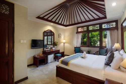 勒吉安Royal Tunjung Hotel & Villa Legian - CHSE Certified的一间卧室配有一张大床和电视