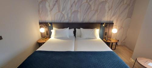莱昂西尔肯路易德里昂酒店的一间卧室配有一张带两盏灯的大型白色床。