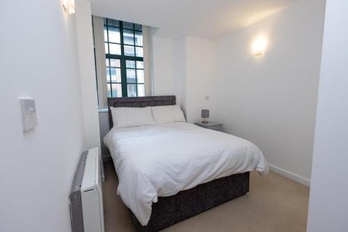 莱斯特Must See One Bed Leicester City Centre Apartment的一间卧室配有一张带白色床单的床和一扇窗户。