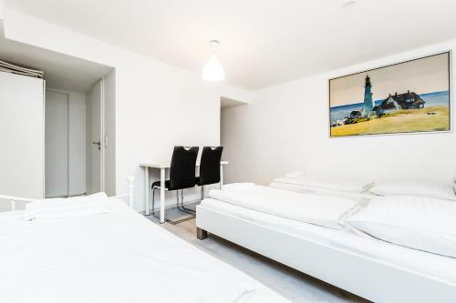 科隆Easy Apartments Work and Stay Cologne的一间白色卧室,配有两张床和一张书桌