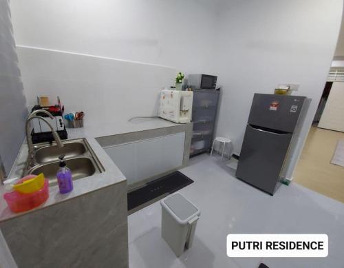 哥打巴鲁PUTRI RESIDENCE的一间带水槽和冰箱的小厨房
