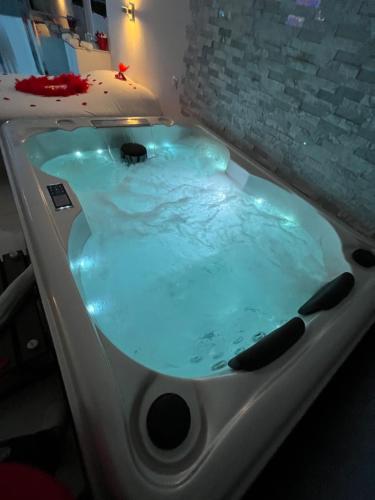 乐罗夫Love room avec spa privatif的客房内的按摩浴缸拥有蓝色的灯光