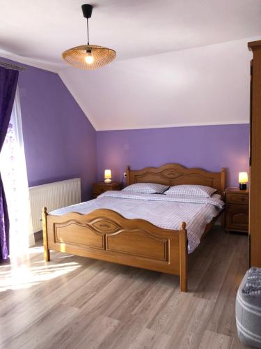 克利默内什蒂Casa Sofia的一间卧室设有一张木床和紫色的墙壁