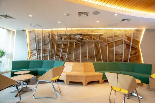利马ibis Styles Lima Benavides Miraflores的一间设有绿色沙发和椅子的等候室