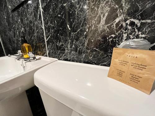 莫法特巴克卢阿姆斯酒店的浴室设有水槽和白色卫生间,上面有标志