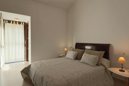 厄尔-汝姆披多Exclusivo Adosado en Punta Coral El Rompido的一间卧室配有一张带两盏灯的床和一扇窗户。