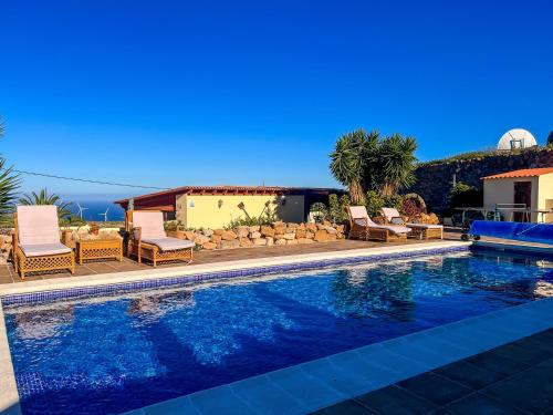Arico ViejoExquisite rural house with garden, pool and sea views的一个带椅子的游泳池以及一座房子