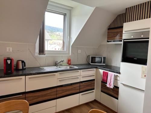 Couvet科维市中心舒适一室公寓的厨房配有白色橱柜、水槽和窗户。