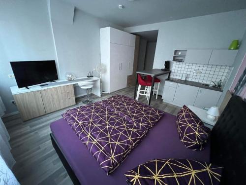 斯图加特MIDTOWN Apartments的一间带紫色床的卧室和一间厨房